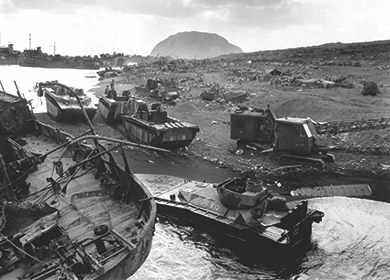 Figure 27.20 American forces come ashore on Iwo Jima. Their vehicles had difficulty moving on the beach’s volcanic sands. Troops endured shelling by Japanese troops on Mount Suribachi, the mountain in the background.